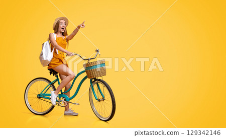 Summer Sale. Excited Young Girl Riding Vintage Bicycle And Pointing Aside At Copy Space Over Yellow Background 129342146