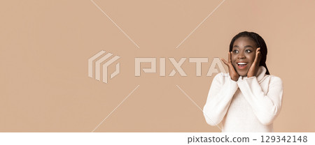 Cute Black Woman Laughing And Touching Her Cheeks On Yellow Background, looking at free space, panorama 129342148