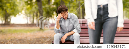 Breakup Concept. Unrecognizable Girlfriend Leaving Sad Boyfriend Sitting On Bench In Park Outside. Cropped, Selective Focus 129342171