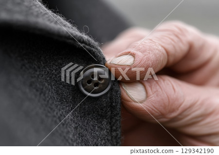 Elderly tailor expertly sewing a button onto a coat in a cozy workshop atmosphere Elderly tailor expertly sewing a button onto a coat in a cozy workshop atmosphere 129342190