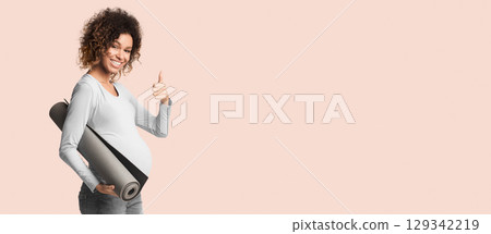 Black pregnant girl holding yoga mat and showing thumb up over white studio background Black pregnant girl holding yoga mat and showing thumb up over white studio background 129342219