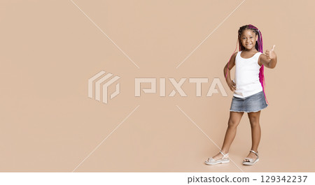 Adorable afro girl gesturing thumbs up on yellow studio background with copy space 129342237