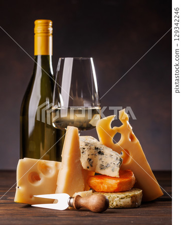 Assorted cheeses paired with glass of wine on a rustic table 129342246