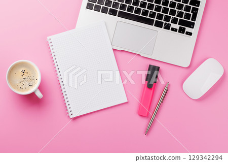 Top view of a pink desk with office supplies, coffee cup, and blank notepad 129342294