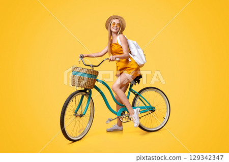 Summer Mode. Full-length Portrait Of Stylish Young Girl Riding Vintage Bicycle And Smiling Over Yellow Studio Background, Free Space Summer Mode. Full-length Portrait Of Stylish Young Girl Riding Vintage Bicycle And Smiling Over Yellow Studio Background, Free Space 129342347