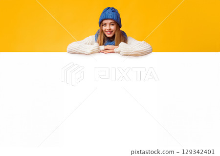 Empty Space For Advertising. Young cheerful girl leaning on empty white board, pink background Empty Space For Advertising. Young cheerful girl leaning on empty white board, pink background 129342401