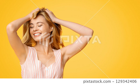 Just Happy. Joyful Teen Girl Touching Her Hair Standing Over Yellow Background, Enjoying Youth 129342406
