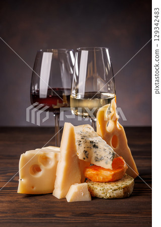 Assorted cheeses paired with glasses of wine on a rustic table 129342483
