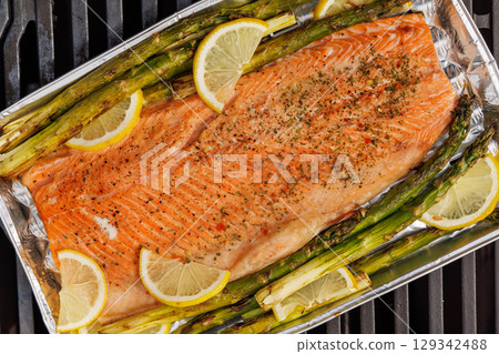 Grilled salmon fillets and asparagus sizzling on a barbecue grill 129342488
