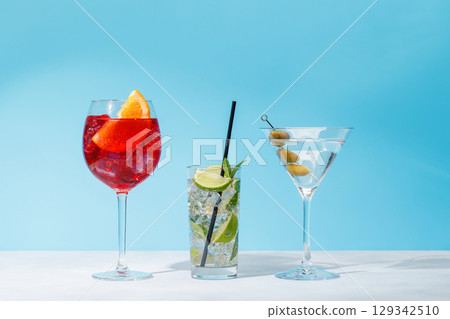 A variety of cocktails arranged on a table against a light blue background 129342510