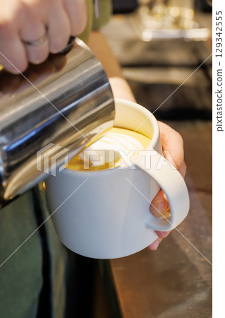 Barista crafting cappuccino with latte art 129342555