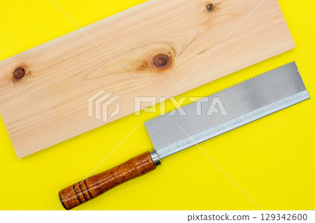 Cypress board and saw on a yellow background 129342600