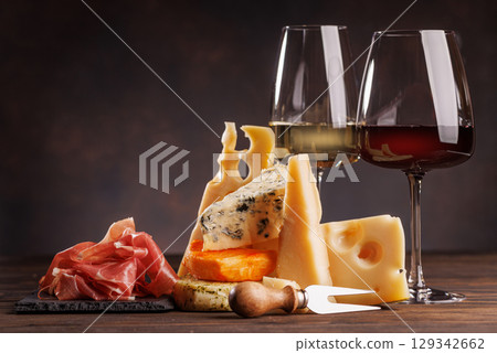 Assorted cheeses paired with glasses of wine on a rustic table 129342662