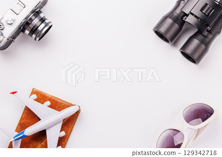Travel-themed flat lay with toy airplane, camera, and sunglasses Travel-themed flat lay with toy airplane, camera, and sunglasses 129342718