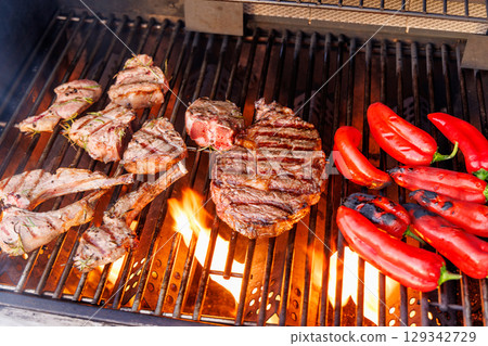 Juicy steaks and bell peppers sizzling on a grill 129342729
