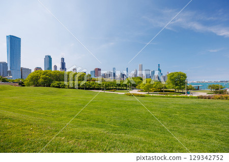 Sunny view of downtown Chicago with iconic skyscrapers rising above a lush green park meadow 129342752