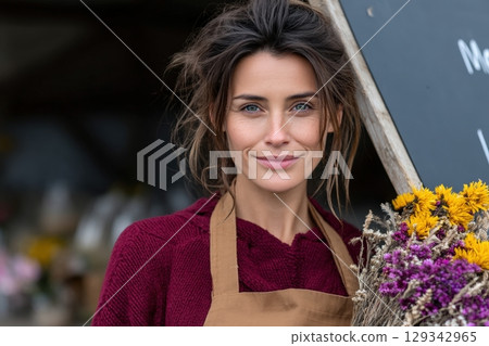 Florist holding a colorful bouquet in a charming flower shop in the morning light 129342965