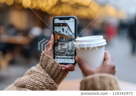 Enjoying a warm drink while scrolling through social media in a cozy outdoor setting 129342973