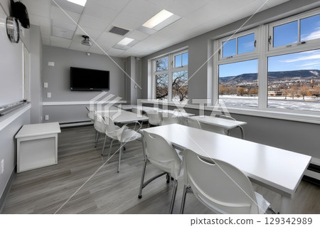 Spacious classroom with large individual desks and bright windows on a sunny day 129342989
