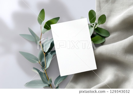 Minimalist design with blank card framed by greenery on a soft, light background 129343032