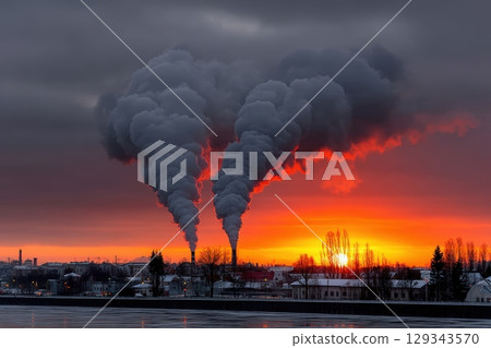 Smoke billows from industrial chimneys at sunset over a frozen river landscape 129343570