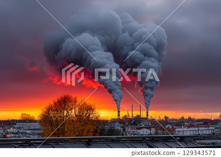 Industrial smoke billows into colorful sunset sky over a cityscape in autumn 129343571