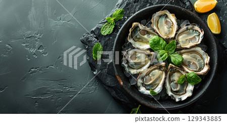 A platter of freshly shucked oysters garnished with mint and lemon wedges invites an elegant seafood experience. 129343885