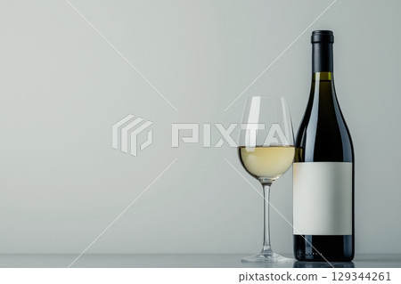 Elegant white wine bottle and glass displayed against a simple background in soft light Elegant white wine bottle and glass displayed against a simple background in soft light 129344261