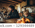 father working at the laptop, little child drawing next to him 129344489