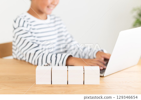 Elementary school boy using a computer at home and a white block Elementary school boy using a computer at home and a white block 129346654