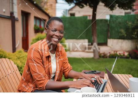 Young black freelancer woman working from home in the garden 129346911