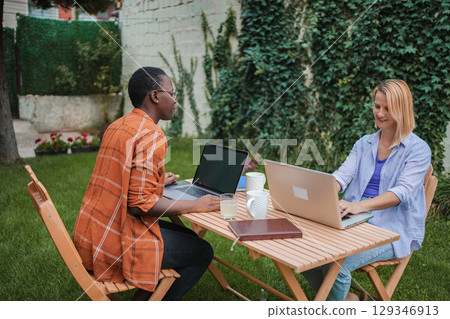 Two Young Businesswomen Working on Laptops in a Garden 129346913