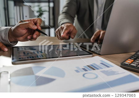 Economics economy Business idea Two people discussing data analysis tablet with financial charts and graphs, professional office setting 129347003