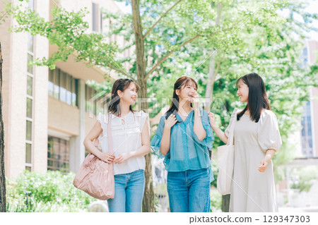 Three college students walking on campus 129347303