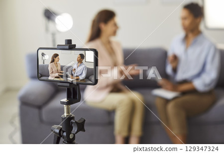 Video interview with influencer, podcast recording for social media with phone camera on tripod 129347324