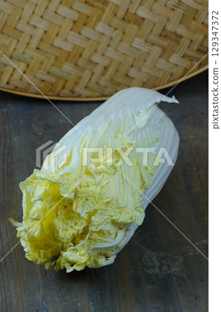 A fresh napa cabbage rests on a rustic wooden table. 129347372