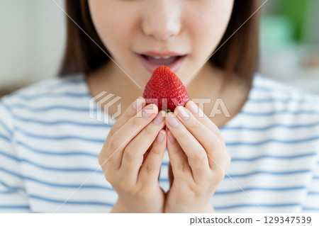 young woman eating strawberry young woman eating strawberry 129347539