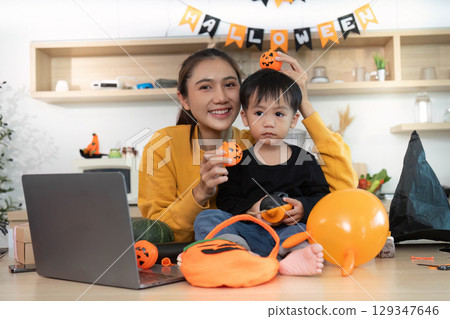 Halloween Celebration. Mother and child decorating for Halloween with festive decorations. Halloween Celebration. Mother and child decorating for Halloween with festive decorations. 129347646