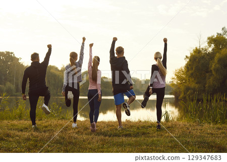 Happy young sport group of people jumping standing in a circle with hands up in nature. Happy young sport group of people jumping standing in a circle with hands up in nature. 129347683