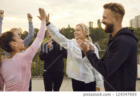 Happy young women giving high five each other rejoicing the success in sport training outdoors. 129347693