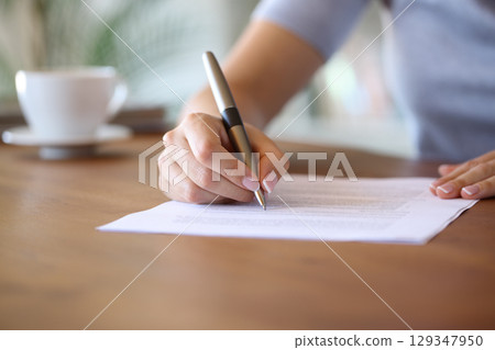 Homeowner hand signing paper contract at home using pen Homeowner hand signing paper contract at home using pen 129347950