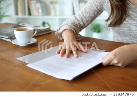 Woman hands sliding paper sheet in transparent plastic file folder 129347970