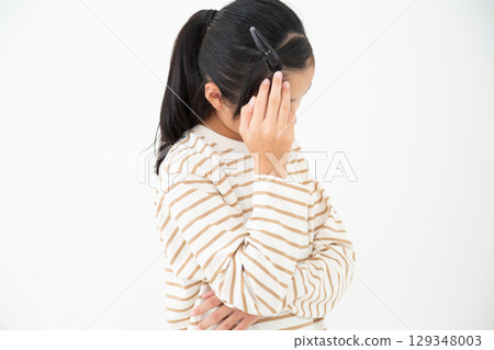 A middle school girl holding her head in pain 129348003