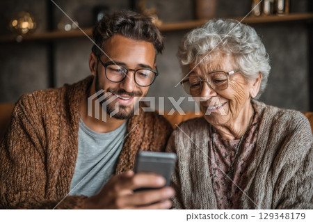 Grandson showing smartphone to smiling grandmother at home 129348179