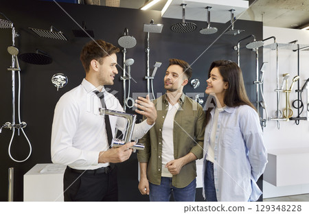 Store Assistant Helping Young Couple Choose Bathroom Faucet 129348228