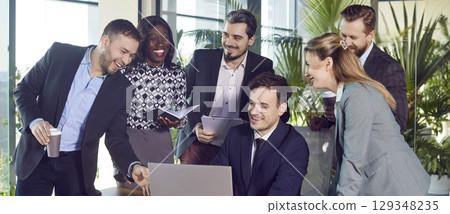 Laughing diverse happy colleagues gather in boardroom at laptop to brainstorm, discuss new plan Laughing diverse happy colleagues gather in boardroom at laptop to brainstorm, discuss new plan 129348235
