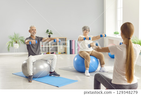 Senior people doing sport exercises with dumbbells with health care worker in rehabilitation center 129348279
