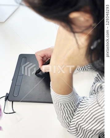 Creative business woman graphic designer working with stylus on digital tablet at modern bright office desk. Freelance artist drawing illustration. Creative professions and productivity concept Creative business woman graphic designer working with stylus on digital tablet at modern bright office desk. Freelance artist drawing illustration. Creative professions and productivity concept 129348293