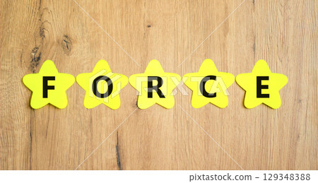 Force symbol. Concept word Force on beautiful yellow paper stars. Beautiful wooden table wooden background. Business lifestyle force concept. Copy space. Force symbol. Concept word Force on beautiful yellow paper stars. Beautiful wooden table wooden background. Business lifestyle force concept. Copy space. 129348388