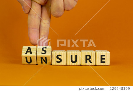 Assure or unsure symbol. Businessman turns wooden cubes and changes the concept word unsure to assure. Beautiful orange table, orange background, copy space. Business and assure or unsure concept. Assure or unsure symbol. Businessman turns wooden cubes and changes the concept word unsure to assure. Beautiful orange table, orange background, copy space. Business and assure or unsure concept. 129348399
